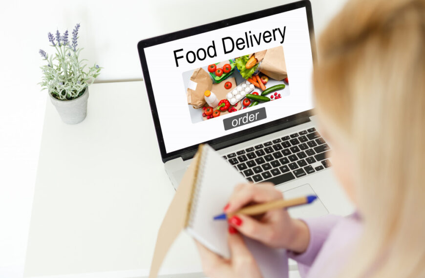 woman making her list in front of a laptop with food delivery site